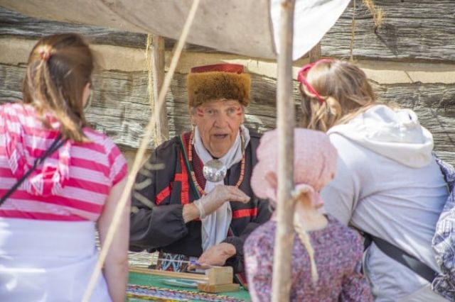 Team member in period attire telling stories to children