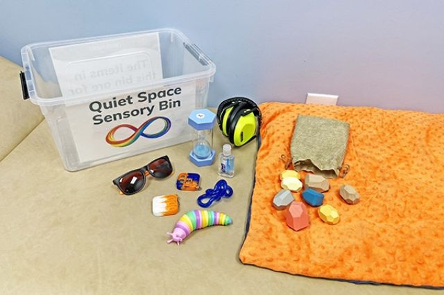a variety of tactile objects for in a clear plastic container labeled quite space sensory bin