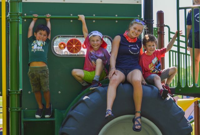 kiddos and a staff member sitting on a big tire